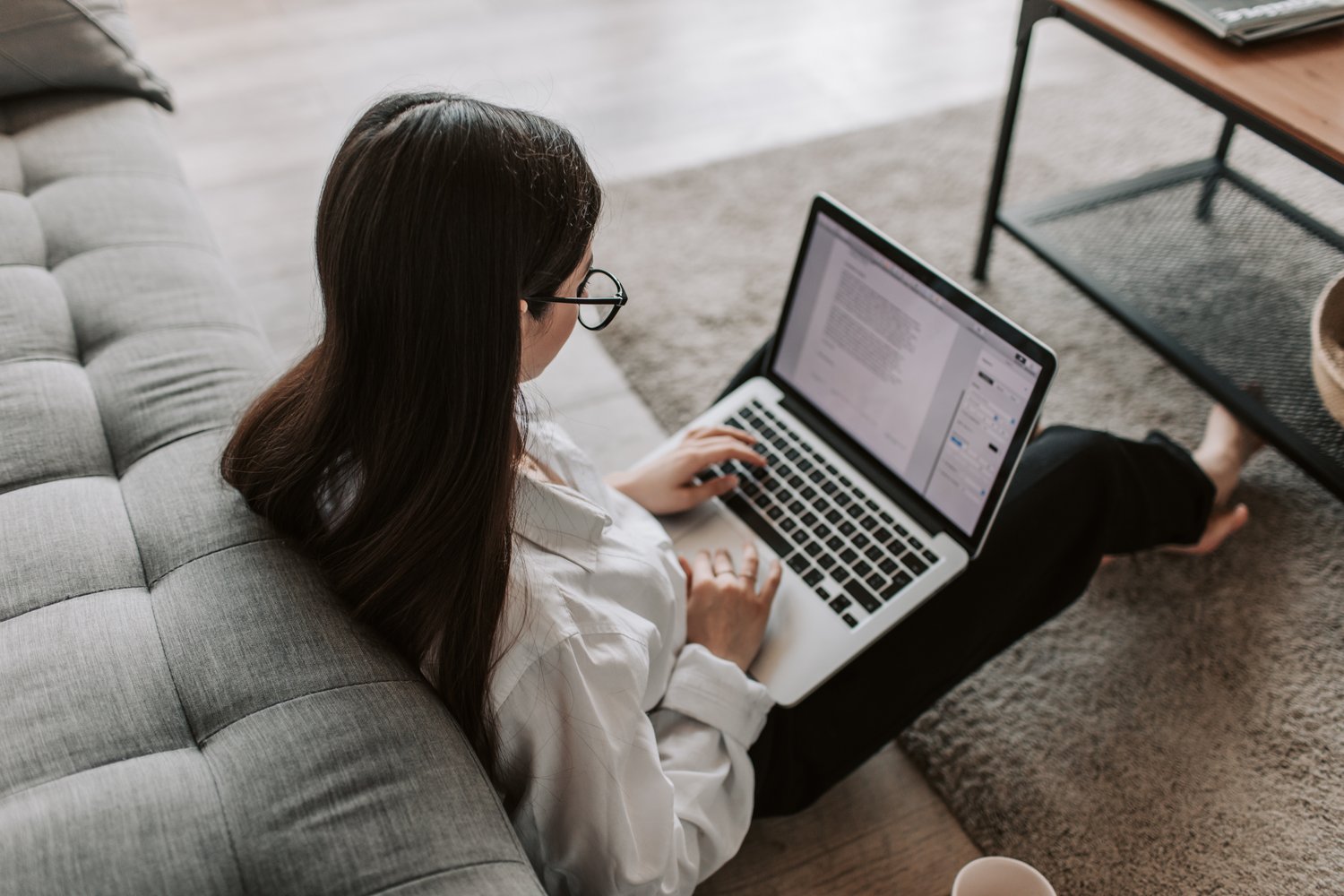 Frau im Wohnzimmer am Laptop beim Durchgehen von Textinhalten