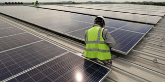 Ein Arbeiter bringt Solaranlagen auf einem Hallendach an